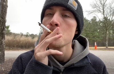 Мужчина с сигаретой делает затяжку